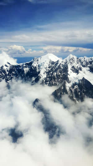 積雪的山峰在藍天下聳立於雲層之上。
