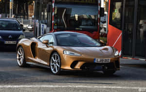 金色McLaren跑車在紅色巴士附近的城市交通中行駛。 — MacBook Pro 13 壁紙