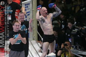 MMA戰士在八角籠中高舉雙臂慶祝勝利。 — 日本 壁紙