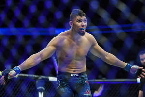 MMA拳手在UFC八角籠中張開雙臂慶祝勝利。
