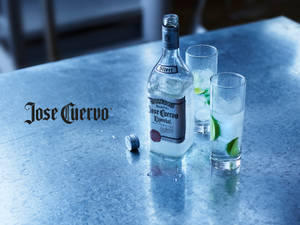 Jose Cuervo龍舌蘭酒瓶和帶有青檸的玻璃杯在金屬吧檯上。