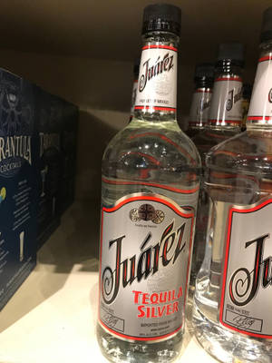 商店貨架上排列的Juarez龍舌蘭酒瓶，附近有一個雞尾酒盒。