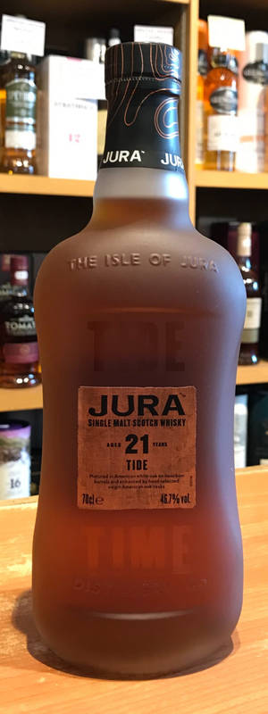 結霜的威士忌酒瓶標示 Jura 21 年，放在木質吧檯上，後方有陳列其他瓶子的層架。 — 電腦 GIF 壁紙