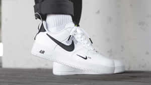 白色Nike Air Force 1波鞋配黑色剔標誌，同坑紋襪一齊放喺木地板上面。