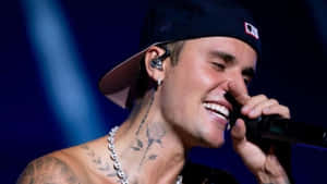 Justin Bieber 在舞台上對著麥克風唱歌大笑。