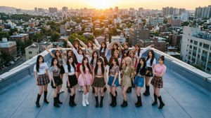 K-pop女團在日落時於天台擺姿勢，背後是城市天際線。