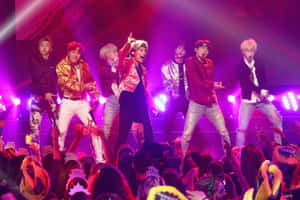 K-pop團體在舞台上表演，粉絲們戴著皇冠在下方。