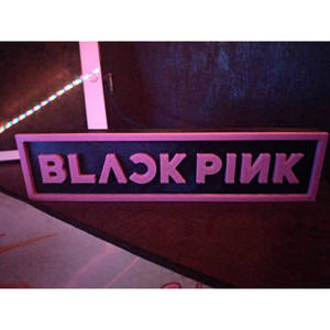在黑暗房間中，帶有LED燈的粉紅色發光BLACK PINK標誌。