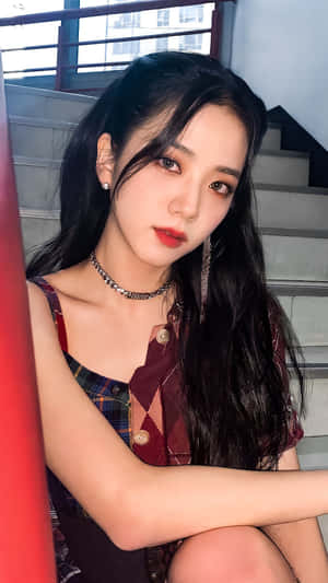 年輕女性穿著格紋上衣和鏈條頸鏈坐在混凝土樓梯上。