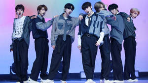 七位年輕男K-pop表演者在燈光舞台上穿著協調的服裝擺姿勢。