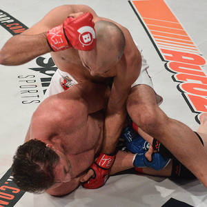 兩名男性拳手在MMA八角形墊上陷入纏鬥比賽。