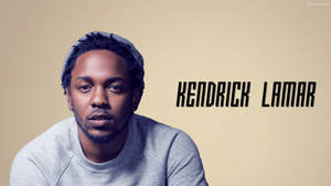 Kendrick Lamar 戴住灰色冷帽同運動衫，米色背景上有名字文字。