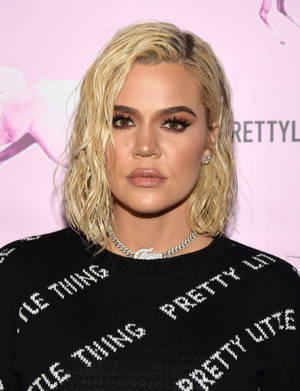 Khloé Kardashian 在粉紅色品牌活動中穿著帶有白色文字的黑色毛衣。 — 金·卡戴珊 壁紙