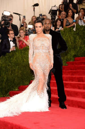 Kim Kardashian 身穿白色羽毛長裙，與 Kanye West 在紅地毯上。 — 2:3 壁紙