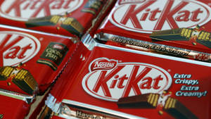 紅色KitKat朱古力條，帶有'Extra Crispy Extra Creamy'文字和金色箔紙包裝。 — 糖果 GIF 壁紙