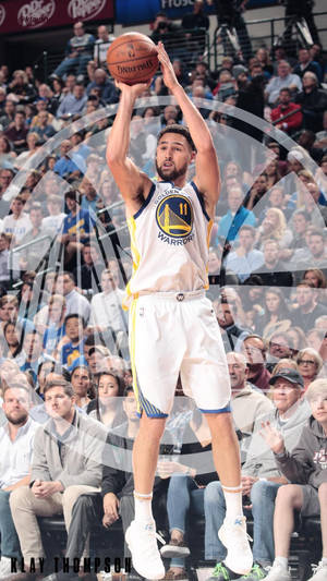 Klay Thompson 在擠滿觀眾的場館中投籃，身穿金州勇士隊球衣。