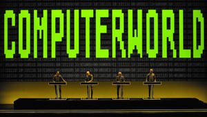四個穿西裝的人物在講台上，發光綠色「COMPUTERWORLD」文字與二進制代碼背景。 — 音樂 GIF 壁紙