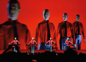 四位身穿紅衫的音樂家在紅色燈光的舞台上彈奏鍵盤。 — 音樂 GIF 壁紙