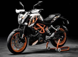 深色工作室中支架上的黑色和橙色KTM Duke電單車。