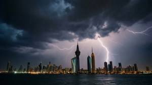 閃電擊中夜晚的現代城市天際線，烏雲密佈，雨水落在水面上。