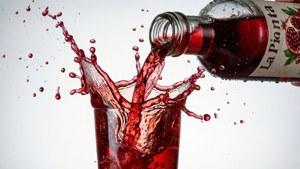紅色石榴汽水倒入玻璃杯，濺起水花