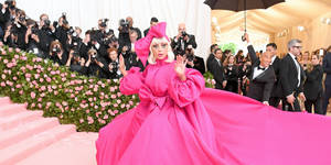 Lady Gaga 身穿粉紅色長袍在 Met Gala 紅地毯活動上揮手。