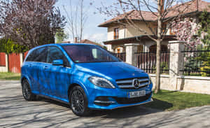 藍色 Mercedes-Benz 旅行車停泊在櫻花盛開的房子前。 — Steam Deck OLED 壁紙