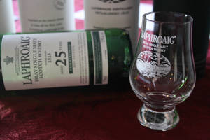 Laphroaig 25年威士忌酒瓶和品酒杯在紅色天鵝絨上。