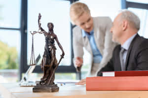 辦公室桌上的青銅正義女神像，背景有律師