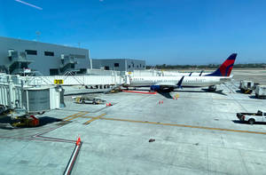 達美航空飛機在機場31B閘口，陽光普照的停機坪上，有登機橋和地面車輛。