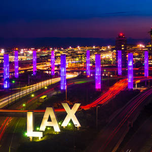 夜晚的洛杉磯國際機場（LAX），紫色發光柱和移動車輛的光跡。