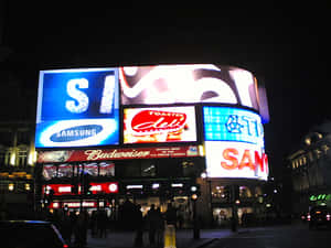 夜晚繁忙城市中燈火通明的廣告牌，下方有行人。 — 夜景城市 壁紙