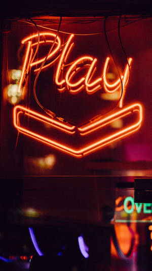 一個發光的橙色霓虹燈牌，在黑暗的城市環境中顯示「Play」字樣和向下箭頭。 — 火影忍者海報 壁紙