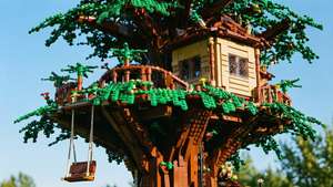 一個LEGO樹屋，有綠色樹葉和一個掛在樹枝上的鞦韆，在藍天下。