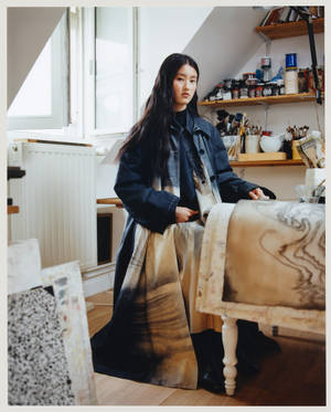 年輕女性在藝術工作室，周圍有畫作和畫筆。