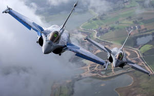 兩架戰鬥機飛越鄉村景觀，下方有田野和河流。