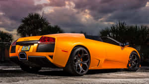 橙色林寶堅尼 Murciélago Roadster 在日落時停泊在棕櫚樹下。 — 蘭博基尼 壁紙