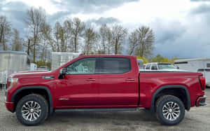 紅色雪佛蘭Silverado AT4皮卡車停放在碎石地上，附近有拖車和光禿禿的樹木。 — Steam Deck 壁紙
