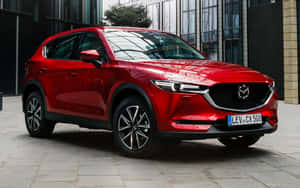紅色Mazda CX-5 SUV停泊在玻璃建築附近的石頭廣場上。 — Steam Deck OLED 壁紙