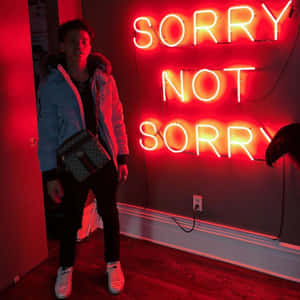 身穿外套和運動鞋的年輕男子站在寫著 sorry not sorry 的紅色霓虹燈標誌前。
