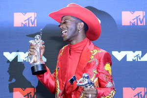 戴紅色牛仔帽和夾克的男人在活動中手持MTV獎項。