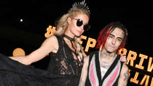 Paris Hilton 與饒舌歌手 6ix9ine 在一個有發光標誌的華麗夜間活動中。