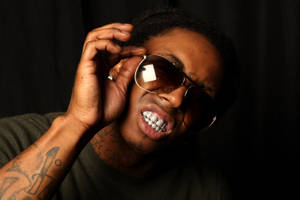 有紋身和金色牙套的男子在攝影棚調整太陽眼鏡。 — Lil Wayne 壁紙
