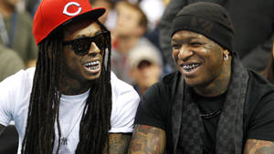 兩位微笑的男子，帶有紋身和太陽眼鏡，在公共活動中。 — Lil Wayne 壁紙