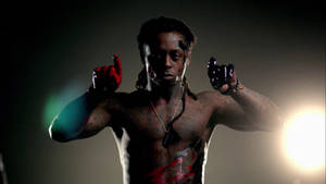 一個有紋身同血跡嘅男人，喺強光下用兩隻食指指向前方。 — Lil Wayne 壁紙