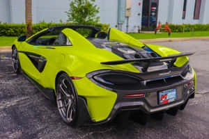 青檸綠色McLaren跑車停泊在建築物和棕櫚樹附近的戶外。 — MacBook Air 13 壁紙