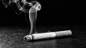 在黑暗表面上冒煙的香煙，旋轉的煙霧在黑色背景下升起。