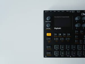 黑色Digitakt鼓機，帶有橙色按鈕，置於淺灰色背景上。