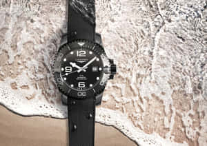 黑色Longines手錶在濕沙上與海浪泡沫