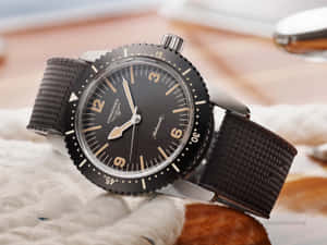一隻黑色 Longines 手錶，帶有銀色點綴和紋理錶帶，放在白色布料表面上。